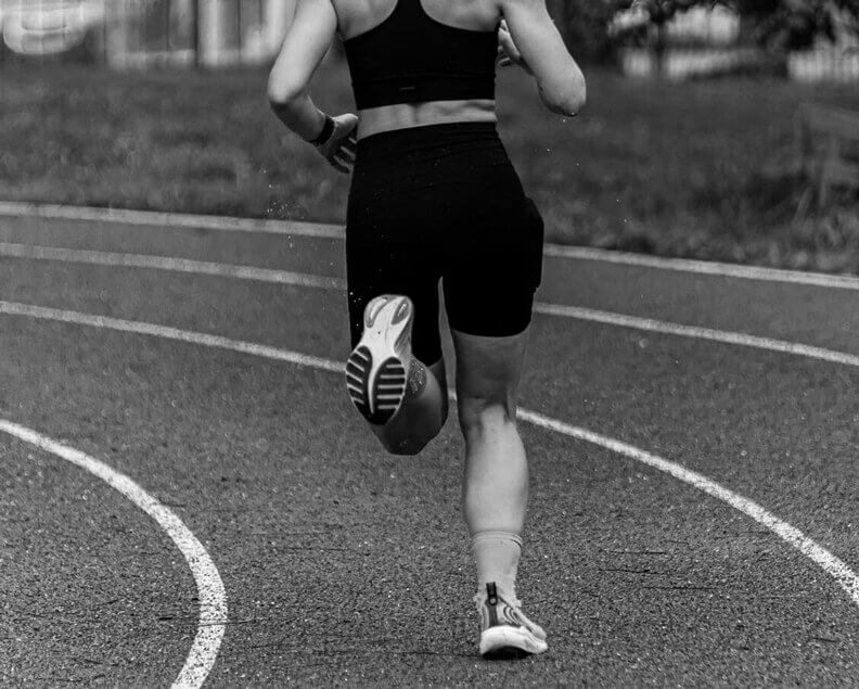 Runner sprinting on a track, photographed from behind