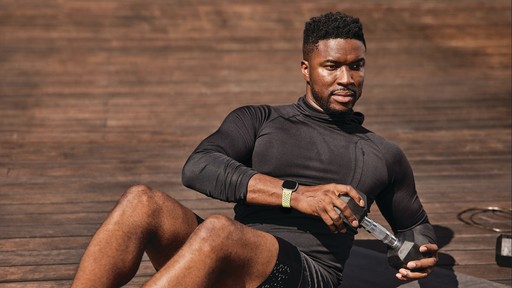 Athlete sitting on a track while checking a phone and smartwatch