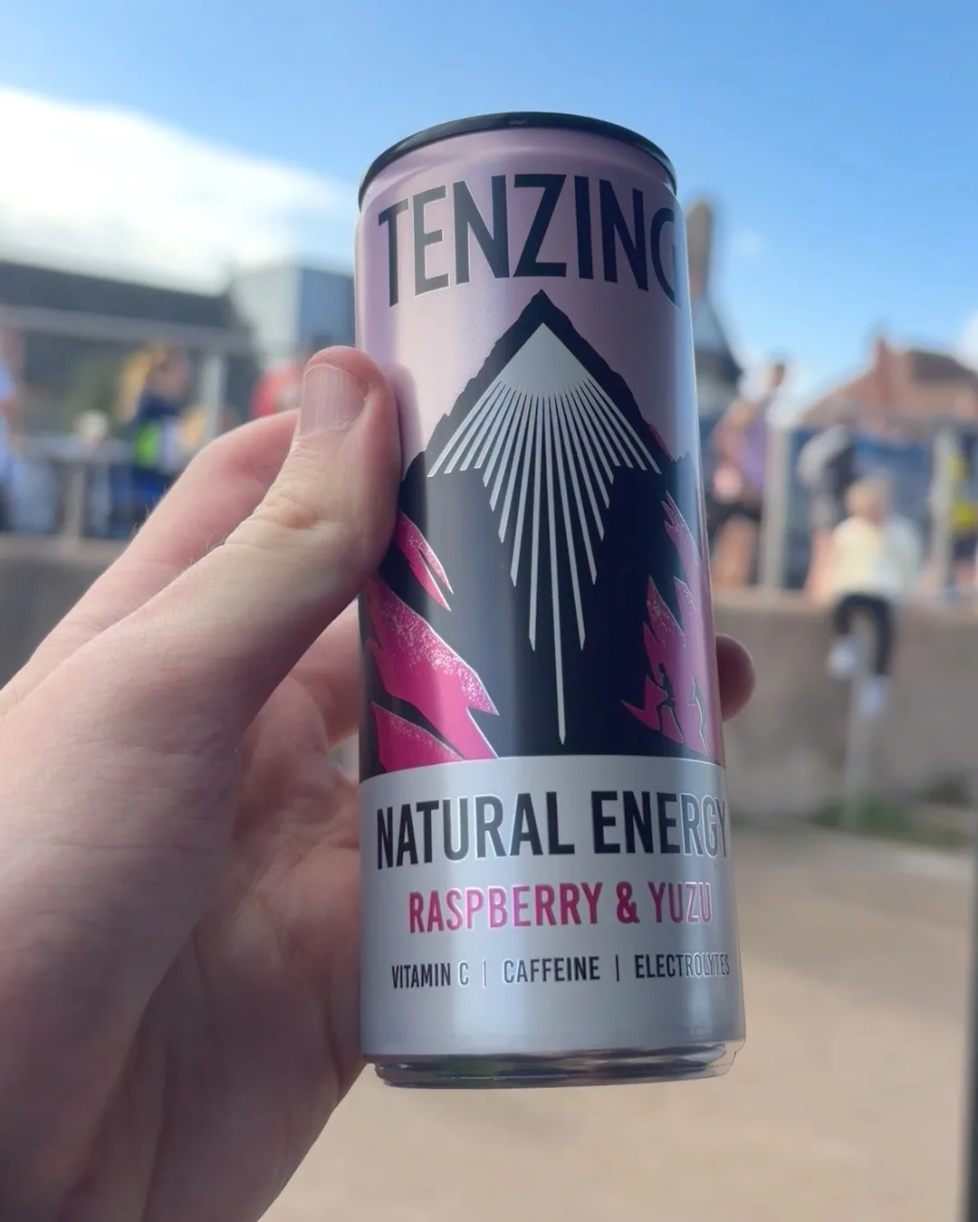 A TENZING Raspberry & Yuzu can held on the Morecambe promenade with runners behind it.
