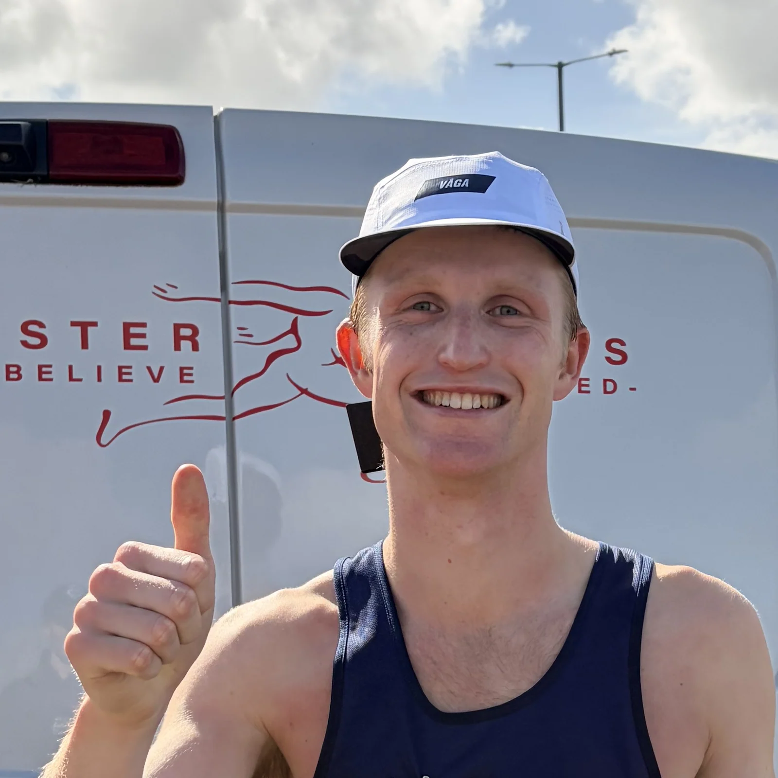 A smiling runner wearing a white VÅGA cap and giving a thumbs-up at the Morecambe event.