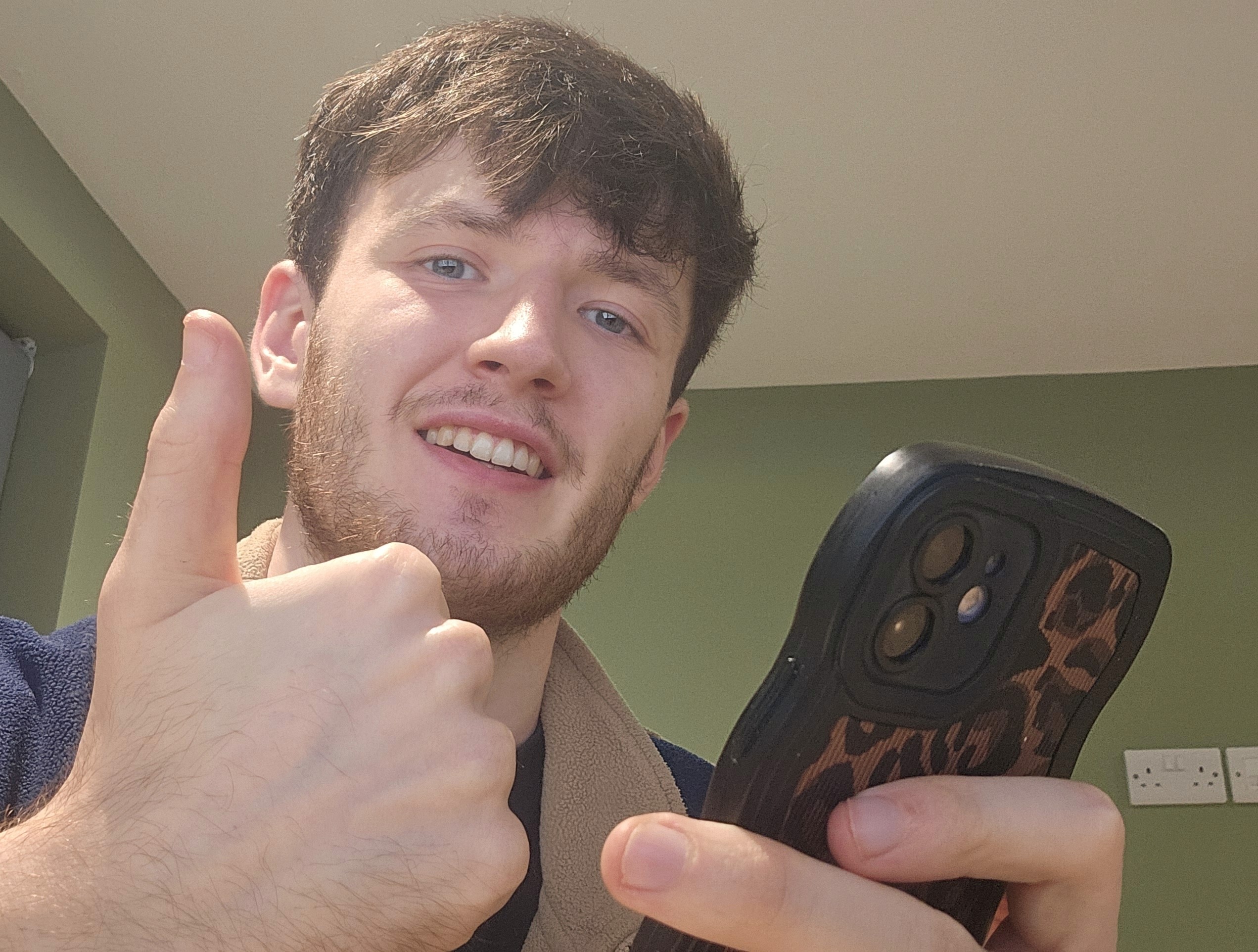 Tim Monteverde holding a phone and giving a thumbs-up