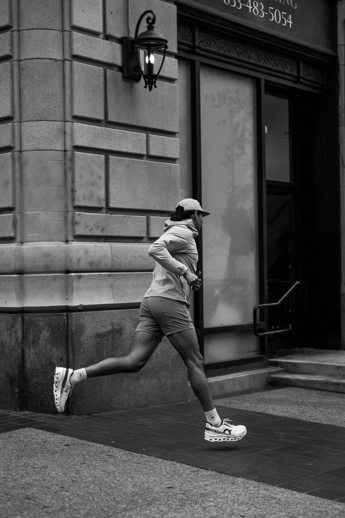 Runner striding past a stone building, mid flight