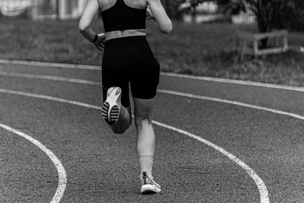 Runner sprinting on a track, photographed from behind