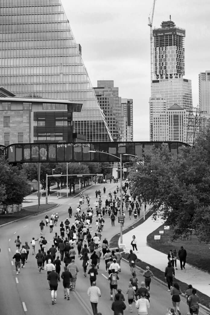 Large pack of runners racing through a city street